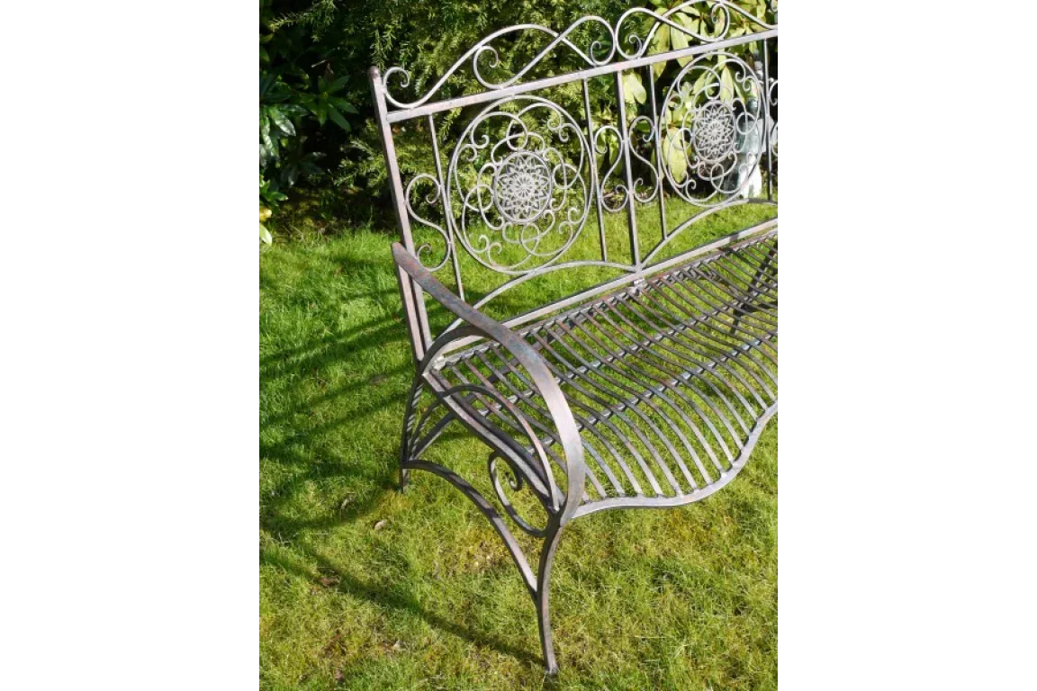 Decorative metal garden bench with ornate scrollwork on grass lawn