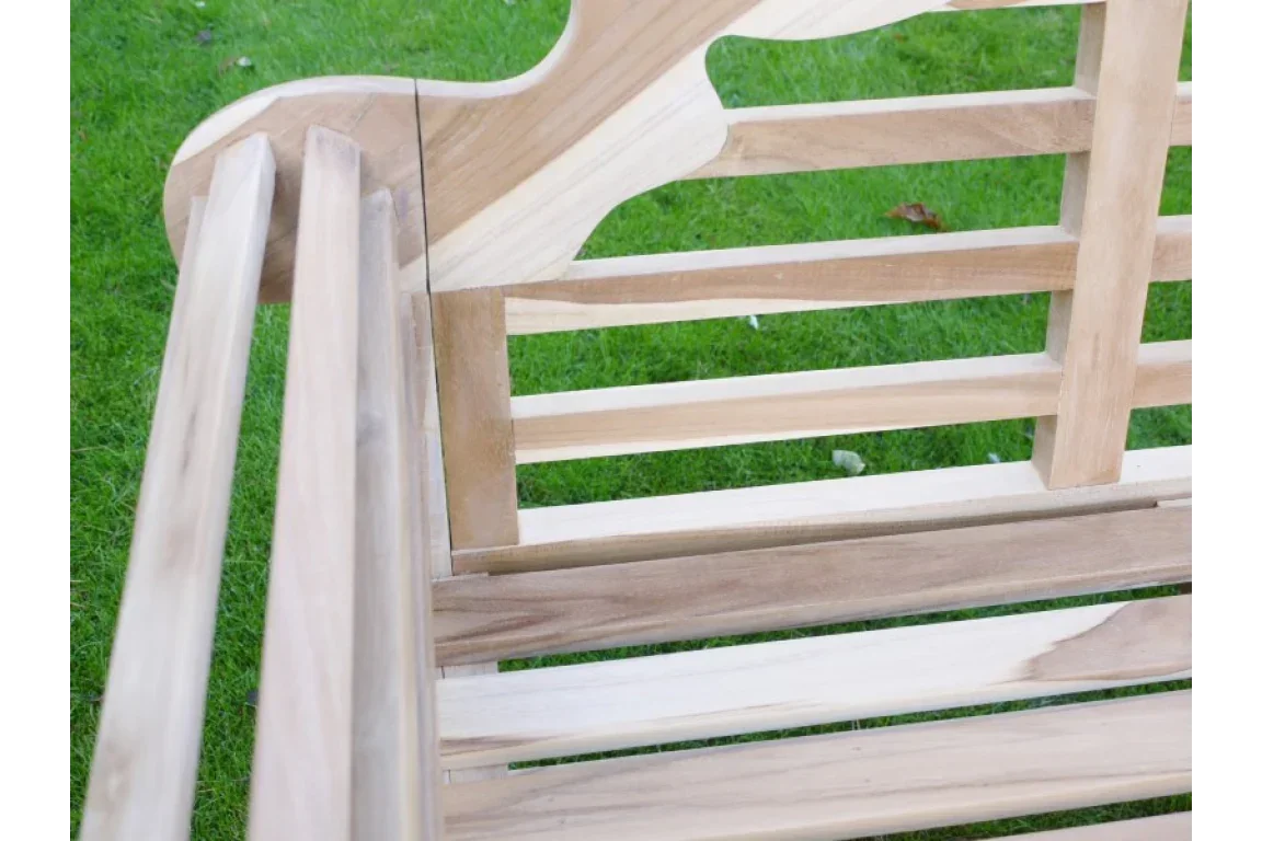 Close up of wooden garden bench slatted seat and backrest on grass lawn