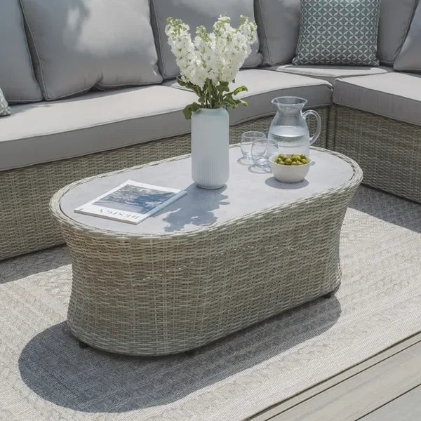 Rattan outdoor coffee table with glass top, vase, drinks and snacks, on patio with sofa