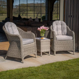 Grey rattan garden chair set with cushions and side table on patio, tulip vase on table