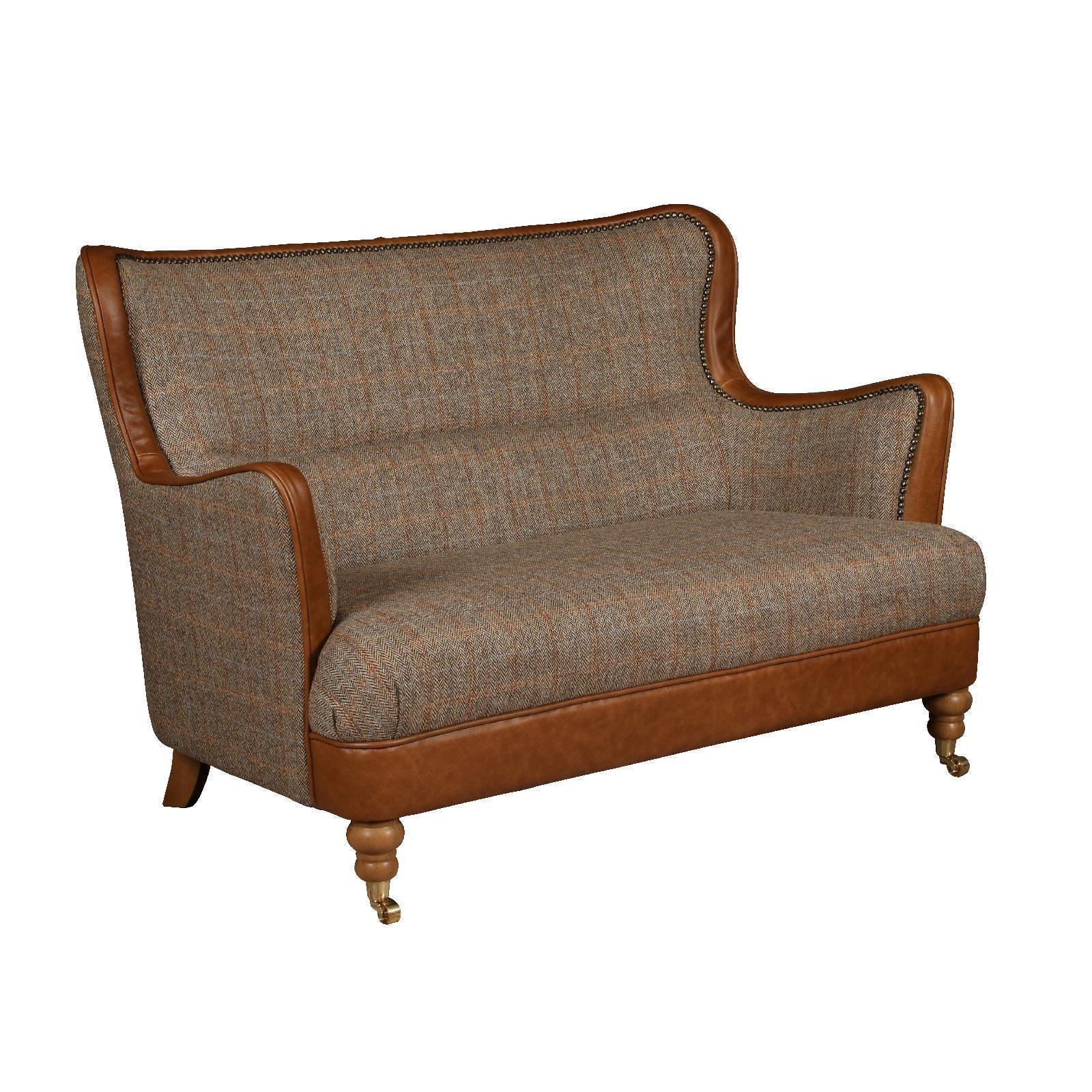 Brown tweed two seater sofa with leather trim and wooden spindle legs on castor wheels