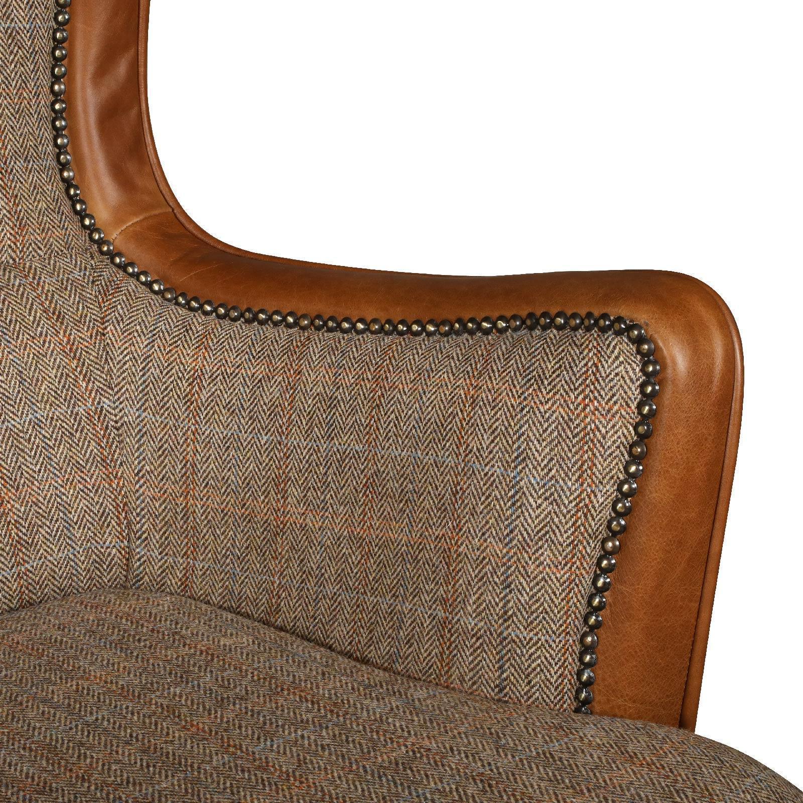 Close-up of tweed and brown leather armchair with brass stud detailing