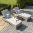 Rattan sun loungers with cream cushions and blue striped pillows on decking patio