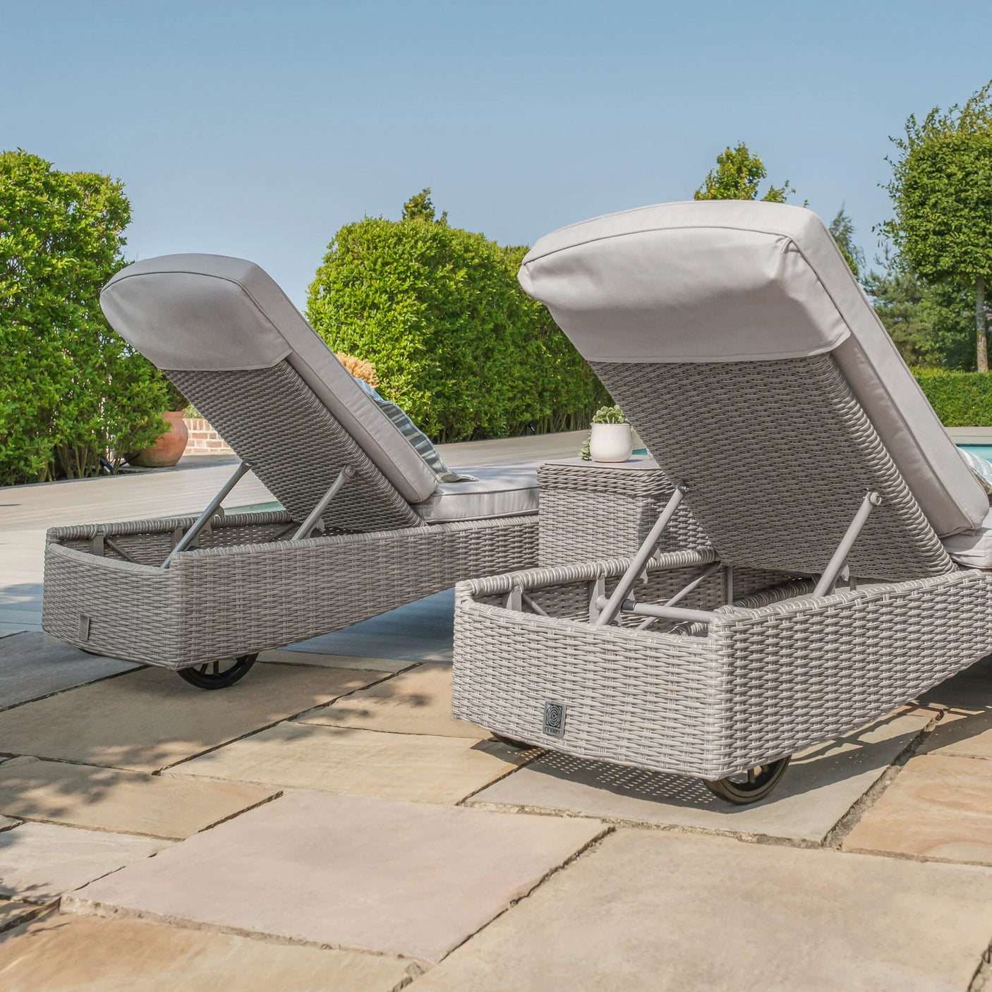 Grey rattan sun lounger set with cushions on patio, adjustable backs, garden setting