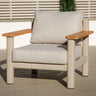 Beige outdoor armchair with light wood armrests and thick cushions on patio