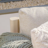 Closeup of outdoor sofa armrest with beige fabric cushion and textured throws