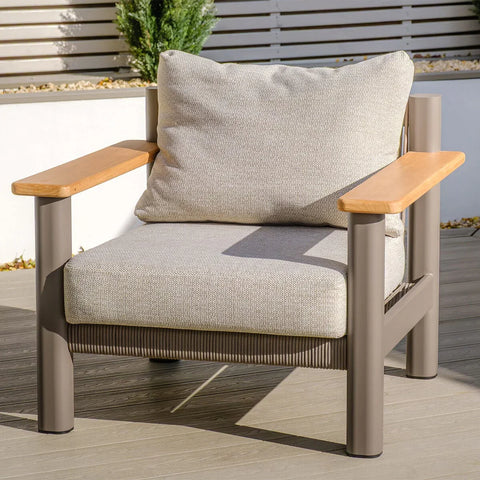 Modern outdoor armchair with beige cushions, metal frame, and wooden armrests on decking