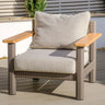 Modern outdoor armchair with beige cushions, metal frame, and wooden armrests on decking