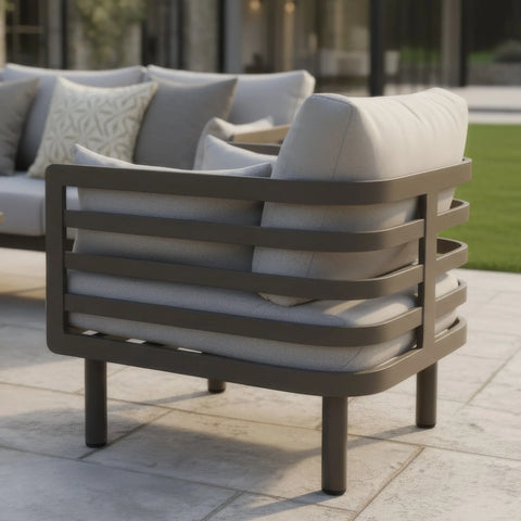 Modern outdoor garden armchair with metal frame and grey cushions on patio