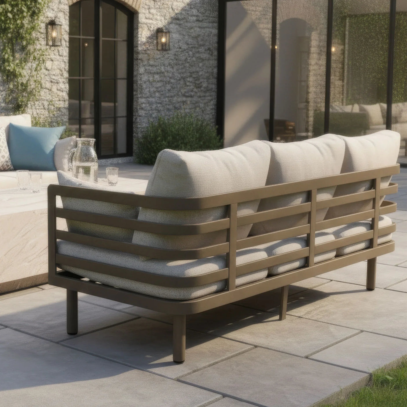 Beige outdoor sofa with metal frame and cushions on a stone patio
