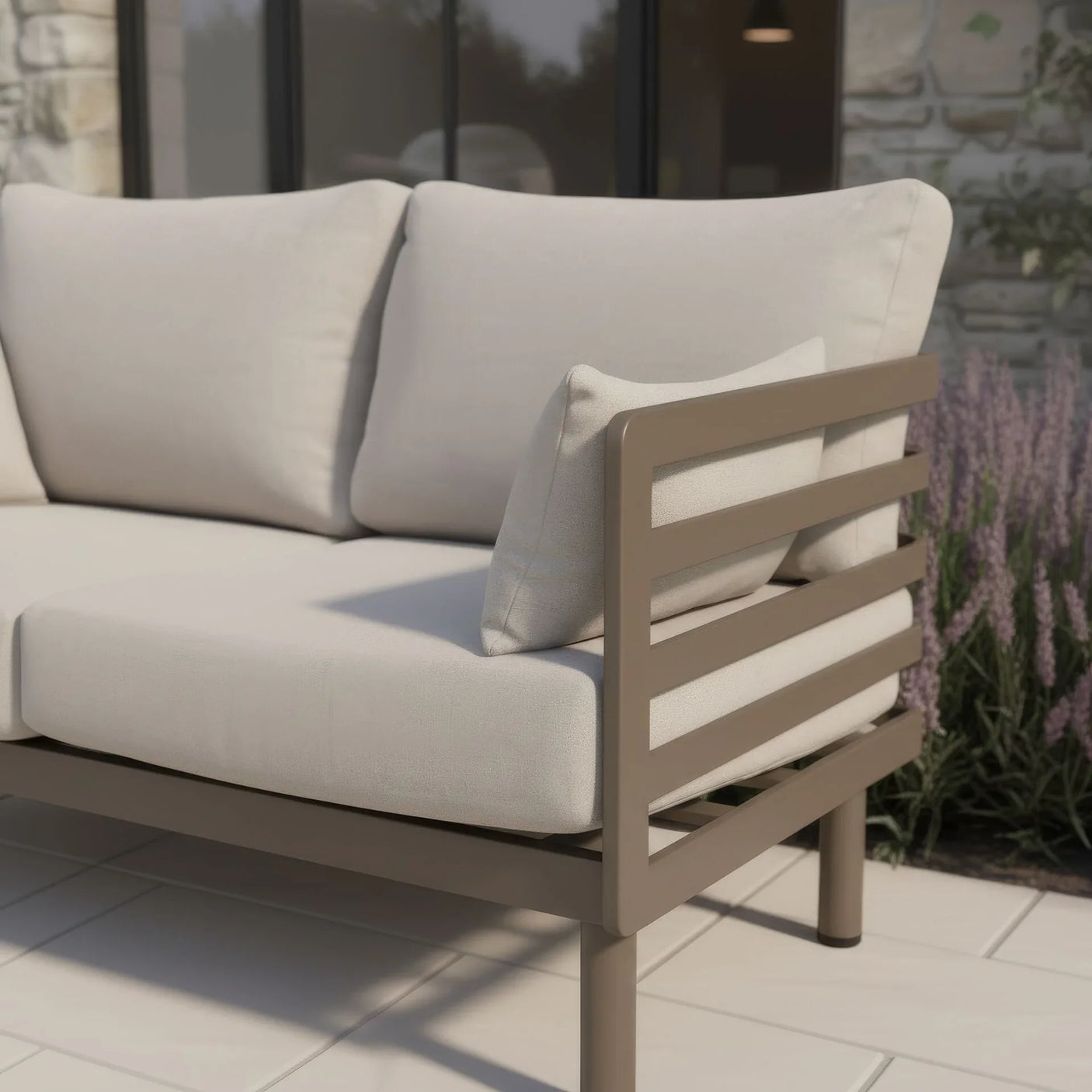 Beige outdoor sofa with metal frame and cushions on patio near lavender plants