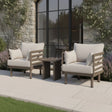 Outdoor garden lounge chairs with beige cushions and side table on stone patio