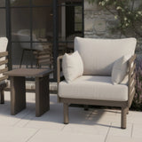 Outdoor armchair with beige cushions and matching side table on modern patio