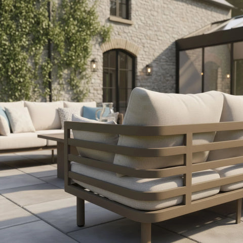 Beige outdoor sofa set with cushions on stone patio, modern metal frame, garden view