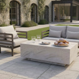 Modern outdoor furniture set with cream cushions and stone coffee table on a patio
