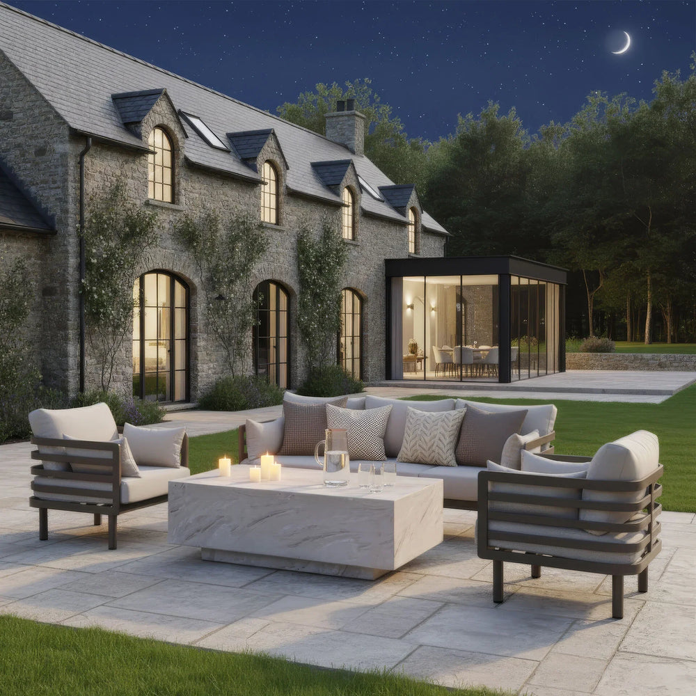 Modern outdoor sofa set with cushions and marble coffee table on a stone patio at night