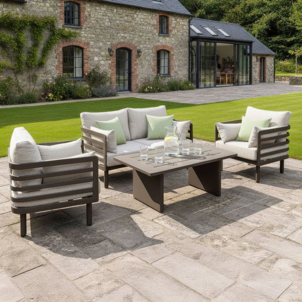 Outdoor patio furniture set with grey armchairs, sofa, and coffee table on stone terrace
