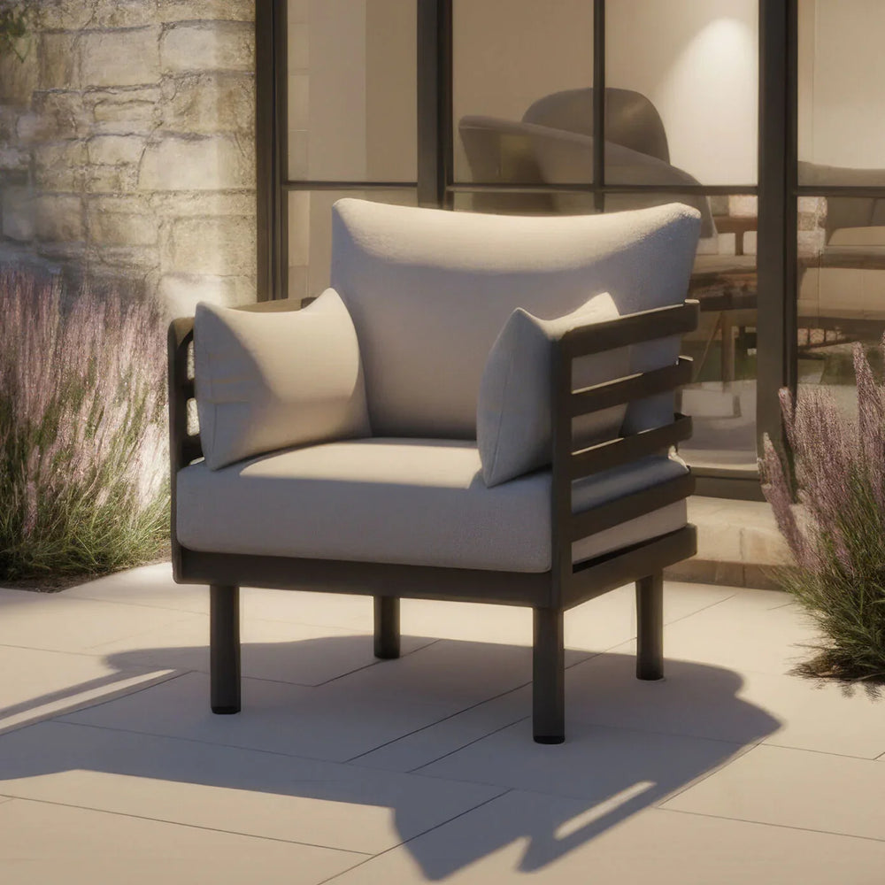 Modern outdoor armchair with grey cushions on patio beside lavender plants