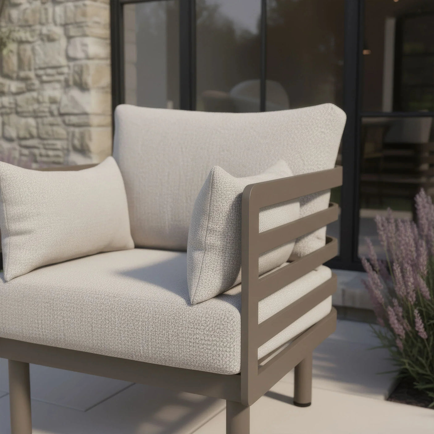 Beige outdoor armchair with thick cushions and metal slatted armrest on patio