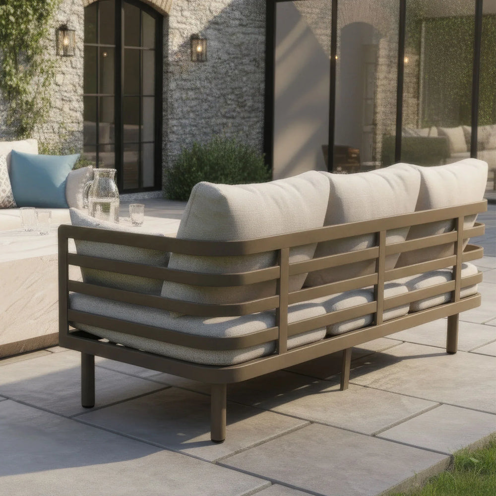 Outdoor sofa with beige cushions and metal frame on stone patio