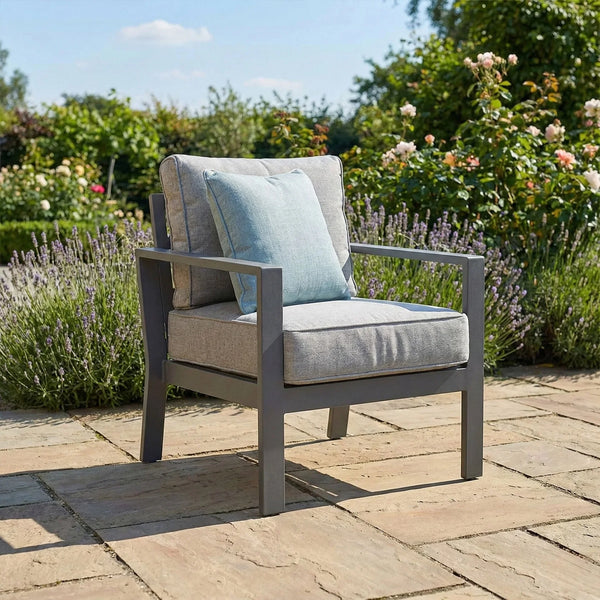 Grey outdoor garden armchair with seat and back cushions on stone patio
