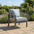 Grey outdoor garden armchair with seat and back cushions on stone patio
