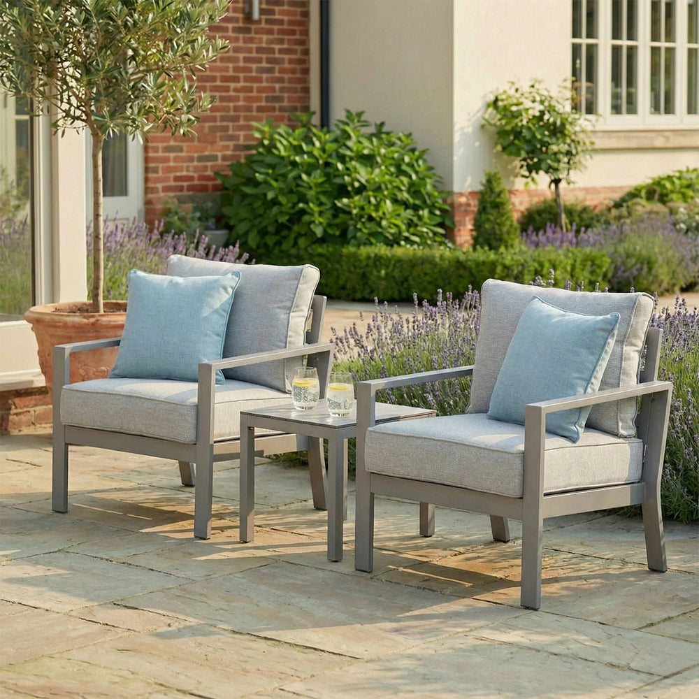 Grey outdoor garden armchair set with blue cushions and side table on stone patio