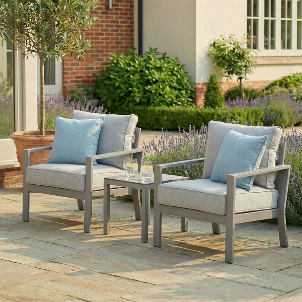 Grey outdoor garden armchair set with blue cushions and side table on stone patio