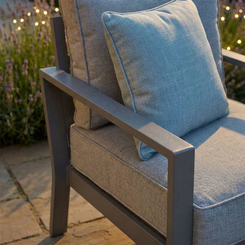 Grey outdoor armchair with metal frame and matching cushion on stone patio