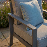 Grey outdoor armchair with metal frame and matching cushion on stone patio
