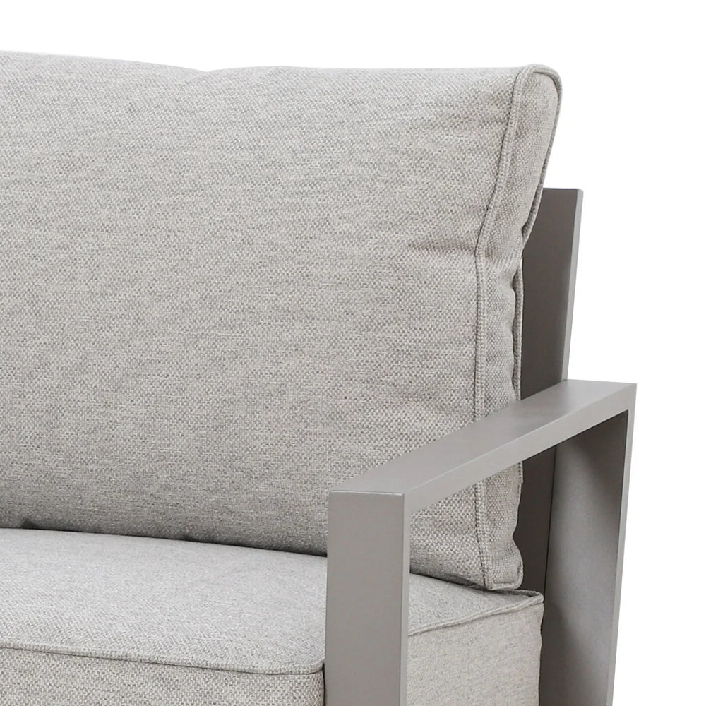 Close view of grey fabric armchair with metal armrest and plush back cushion