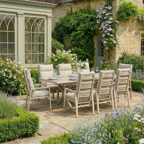 Outdoor dining set with eight cushioned wooden chairs and table on stone patio in garden