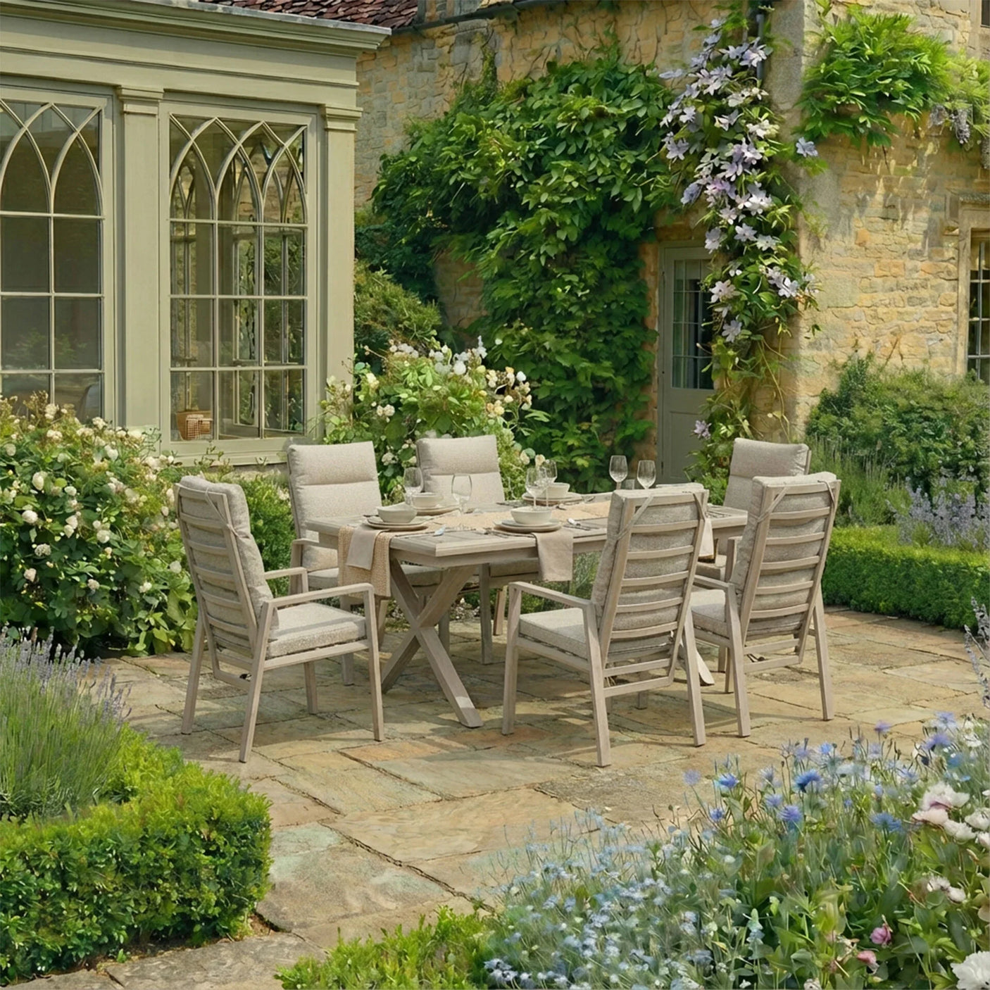Wooden outdoor dining set with six cushioned chairs on stone patio in country garden