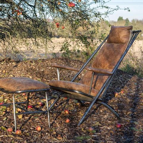 Leather lounge chair with matching ottoman on metal frame outdoors among fallen apples