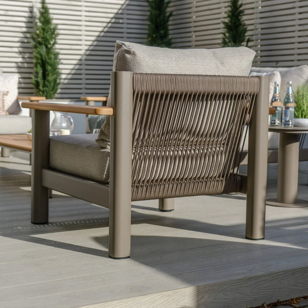 Outdoor rope armchair with taupe cushion and wooden armrest on patio decking