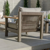Outdoor rope armchair with taupe cushion and wooden armrest on patio decking
