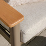 Close view of outdoor sofa with beige cushion and wooden armrest on deck