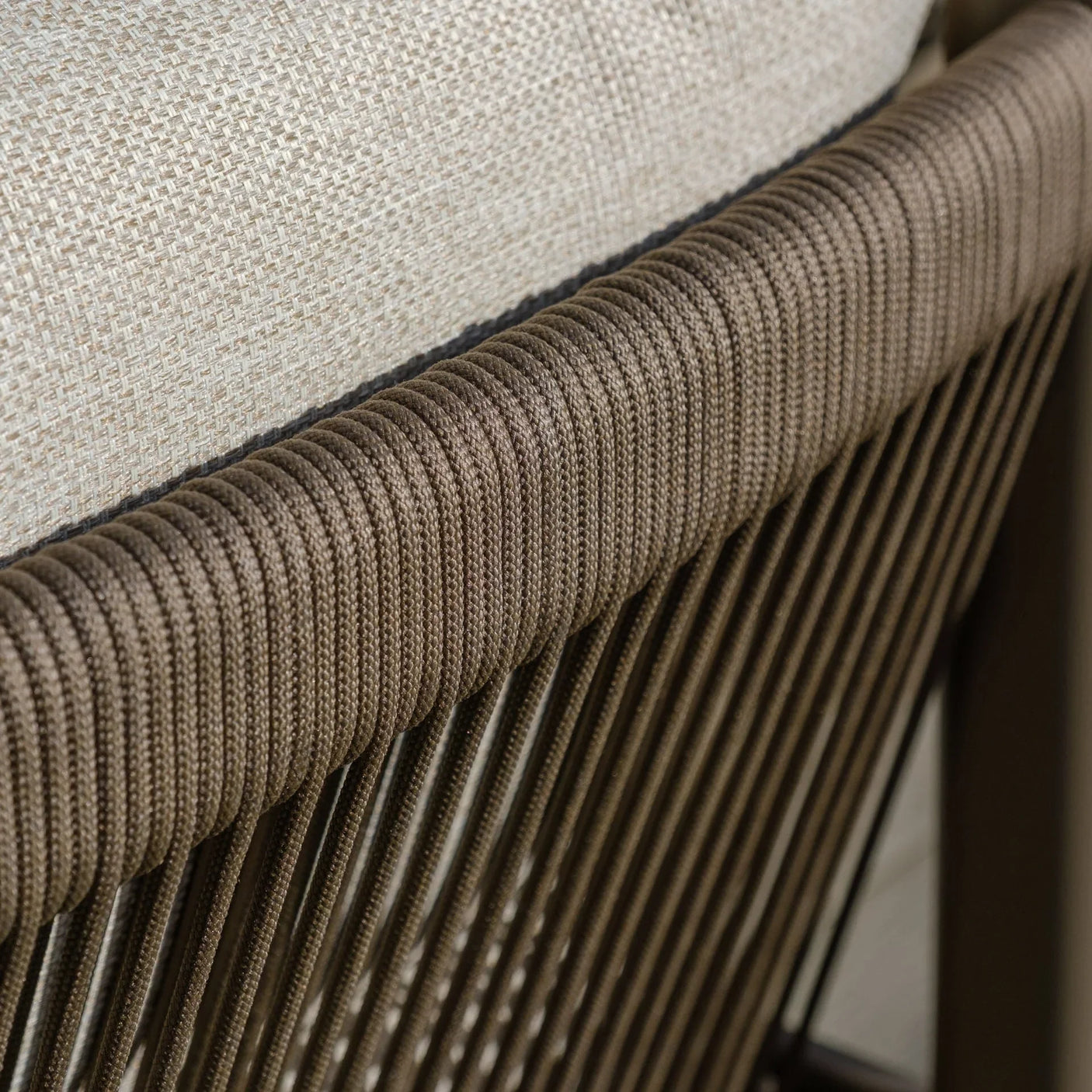 Close view of brown rattan sofa backrest with woven rope detail and beige cushion