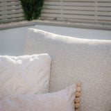Close-up of beige sofa back with textured cream throw pillow and decorative cushion