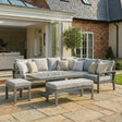 Grey outdoor corner sofa set with cushions, coffee table, bench and stool on a patio