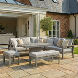 Grey garden corner sofa set with dining table, bench, and cushions on stone patio