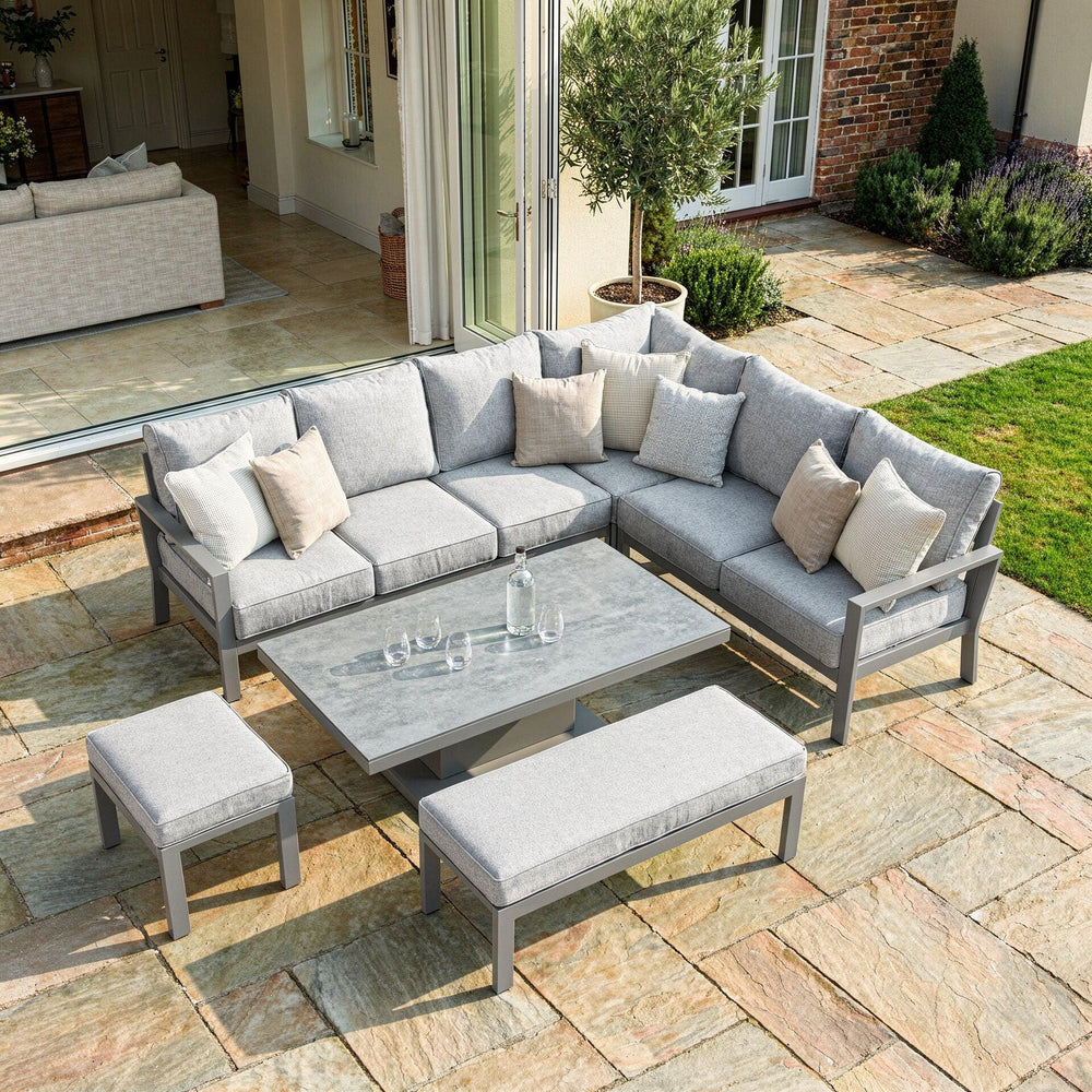 Grey outdoor corner sofa set with matching bench and stool on stone patio