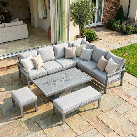 Grey outdoor corner sofa set with matching bench and stool on stone patio