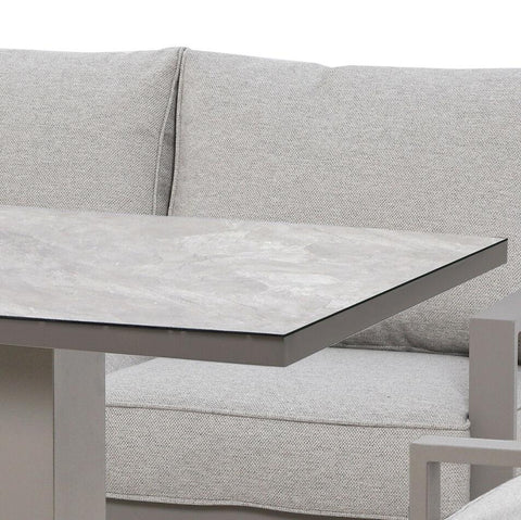 Grey fabric sofa with high back cushions and rectangular stone top table corner