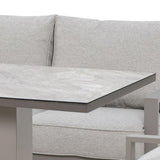 Grey fabric sofa with high back cushions and rectangular stone top table corner