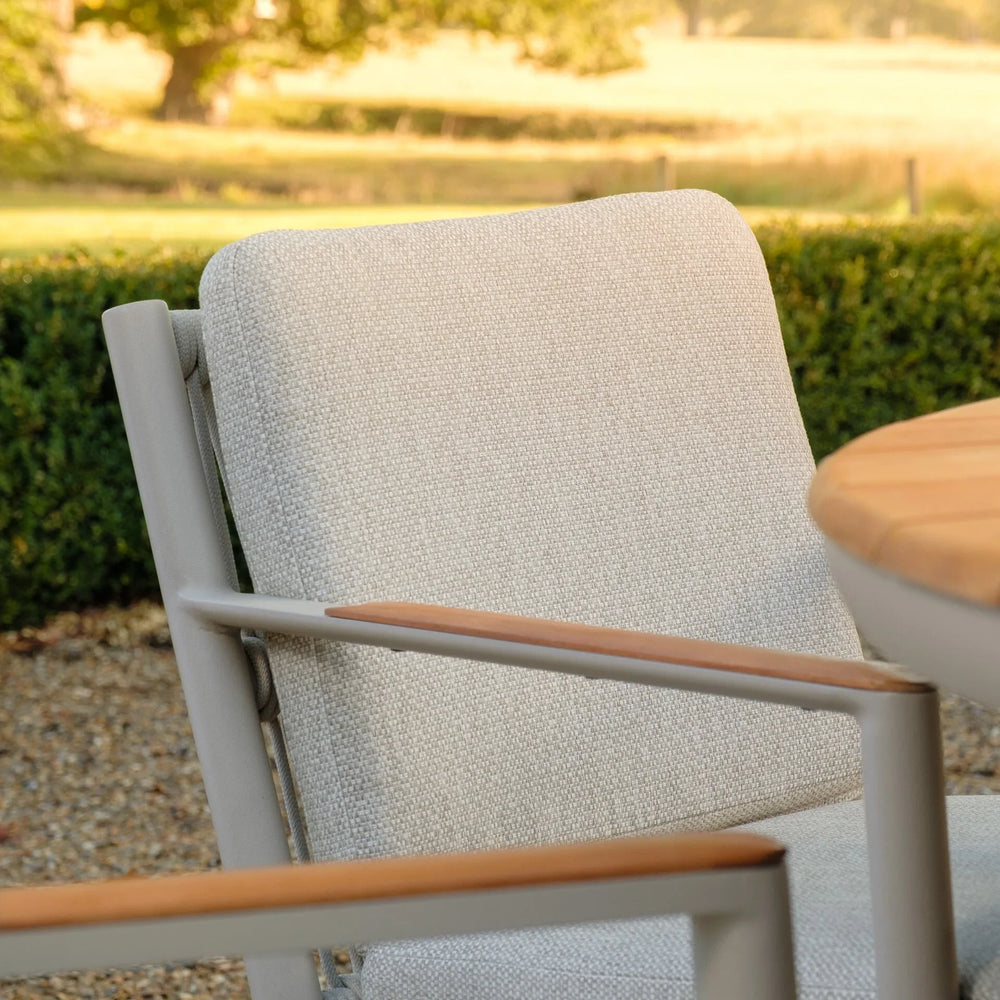 Outdoor dining chair with light beige fabric and wooden armrests beside round table