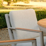 Outdoor dining chair with light beige fabric and wooden armrests beside round table