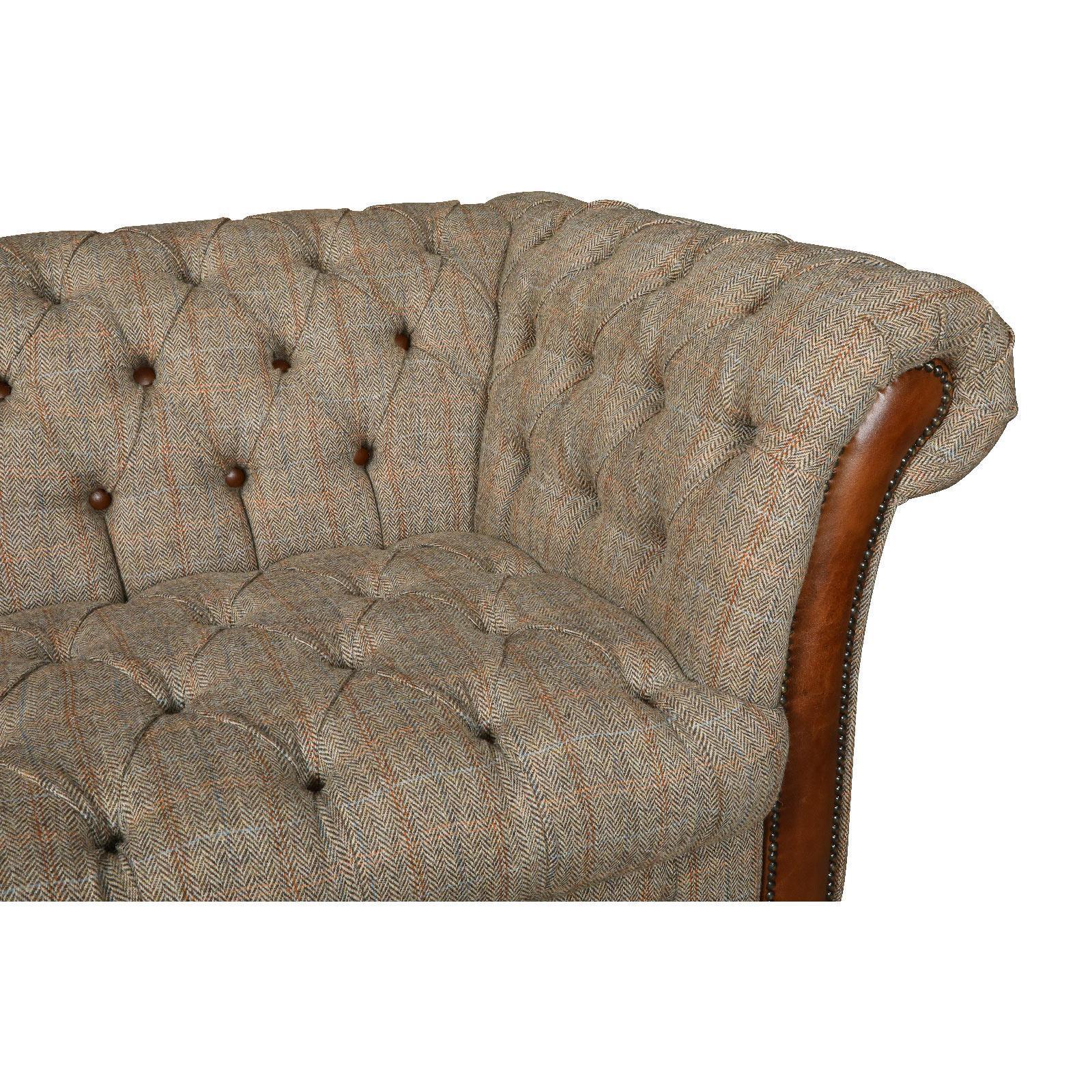 Close-up of a button-tufted fabric sofa arm with brown leather trim and nailhead detail