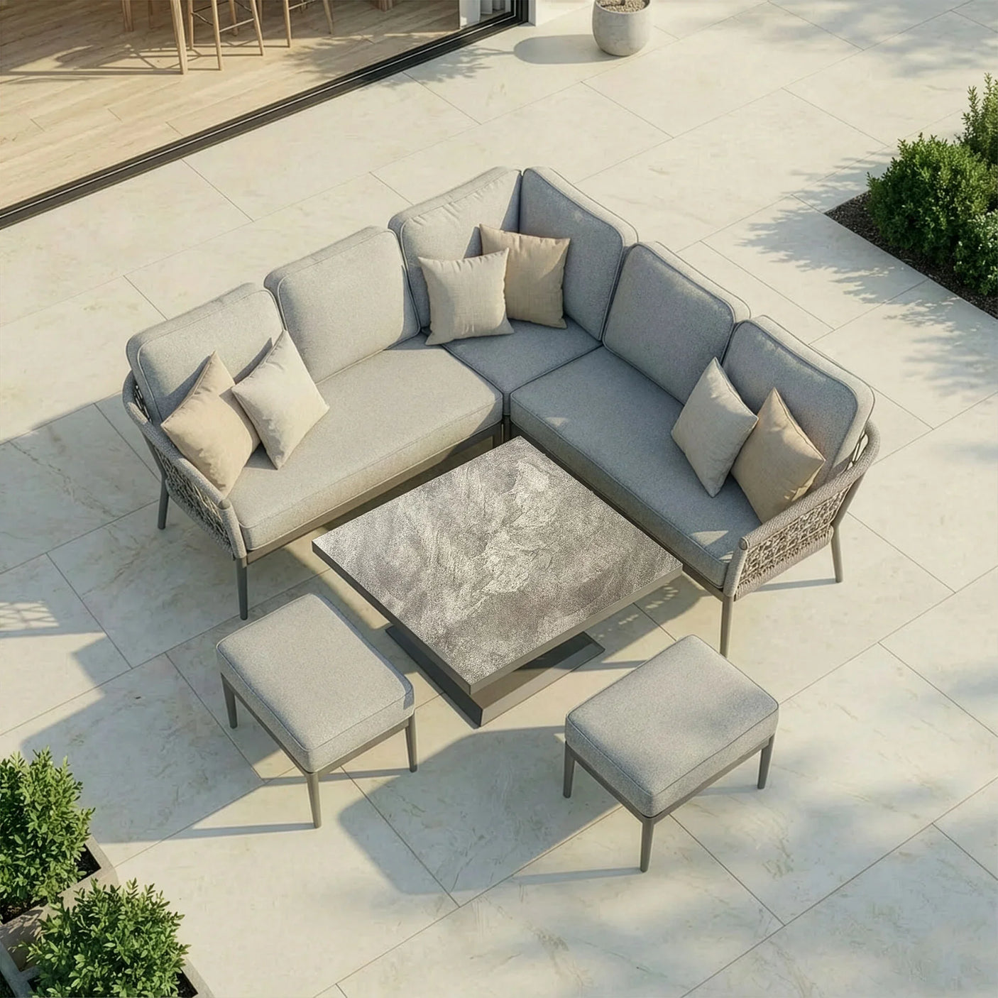 Grey outdoor corner sofa set with cushions, matching stools, and stone-effect coffee table on patio