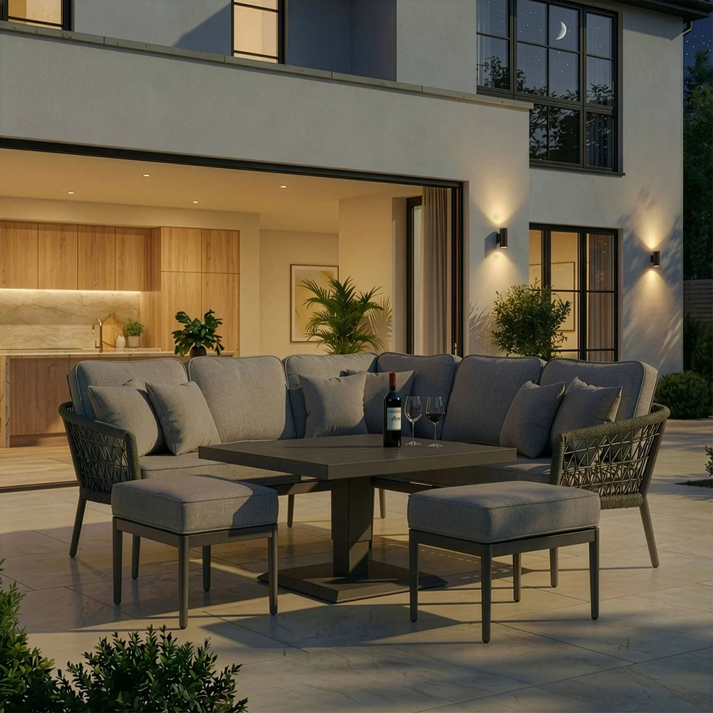 Grey outdoor corner sofa set with coffee table and footstools on a modern patio at dusk